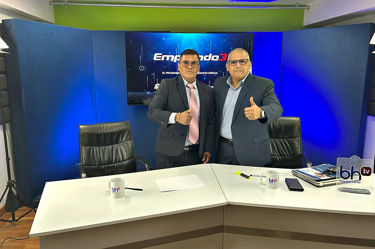 El Dr. Efraín Valverde y el conductor en el set de Emprende3, con el logo de bh tv sobre el escritorio